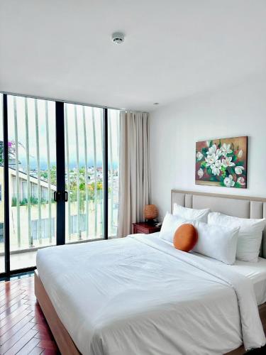 a bedroom with a large white bed with a large window at Len's Hotel in Da Lat