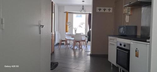 une cuisine avec une table et des chaises et une cuisine avec un four micro-ondes dans l'établissement Opulence Pau, à Pau