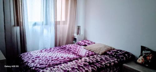 un lit avec une couette violette posée à côté d'une fenêtre dans l'établissement Opulence Pau, à Pau