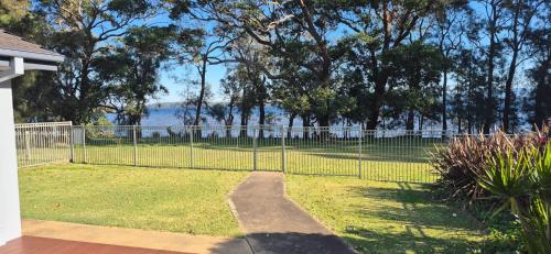 a fence in a yard with a view of the water at Peaceful Waterfront, wheelchair accessible - Stunning Location for Family Holiday in Sanctuary Point