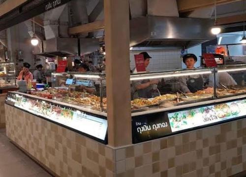 a buffet line with people preparing food in a restaurant at อิมแพ็ค popular condo c5 แม่ตังค์ in Ban Bang Phang