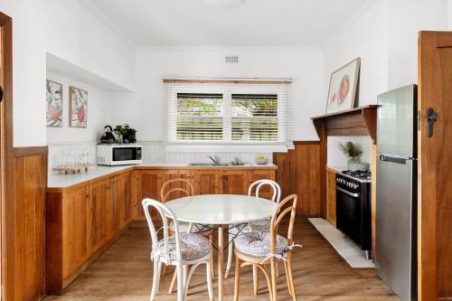 une cuisine avec des armoires en bois et une table et des chaises dans l'établissement Charming 1930s Cottage Retreat I Pet Friendly Escape, à Geelong West