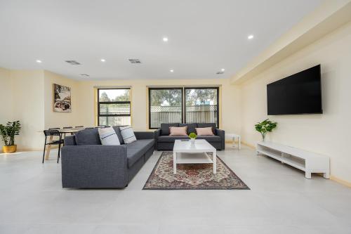 a living room with a couch and a tv at Westmeadow Breeze Skyline Stay 8 Min to Airport in Melbourne