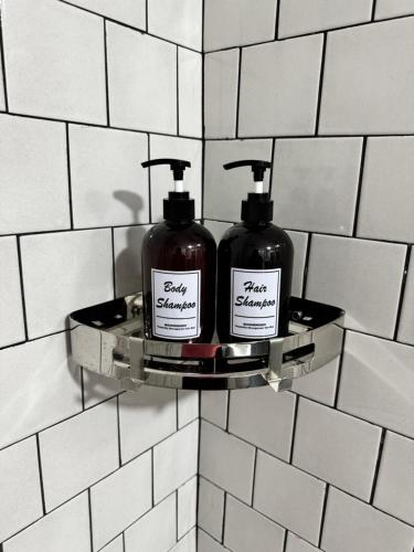 two bottles of soap on a shelf on a bathroom wall at The Harbour by Moonknight in George Town