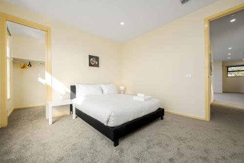 a bedroom with a white bed and a mirror at Westmeadow Breeze Skyline Stay 8 Min to Airport in Melbourne