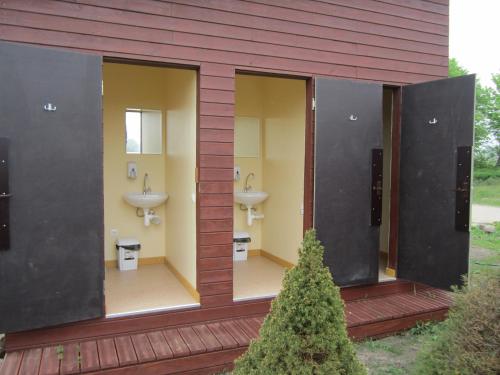 uma casa de banho com dois lavatórios e dois WC num edifício em Kempings "Ceļmalnieki" em Liepāja