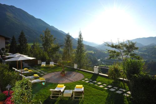 einen Garten mit Stühlen, Sonnenschirm und Bergen in der Unterkunft Alpines Lifestyle Hotel Tannenhof in St. Johann im Pongau