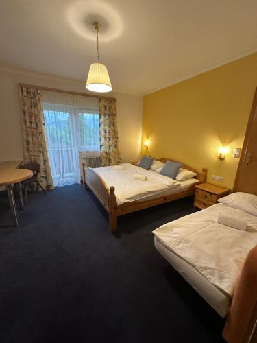 a hotel room with two beds and a table at Pension ALPENHAUS in Vorderstoder