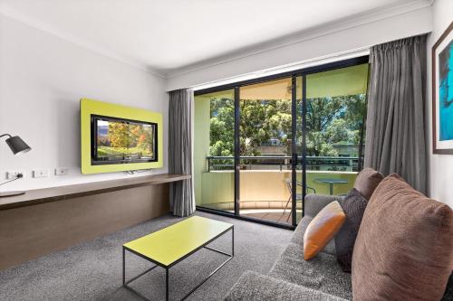 a living room with a couch and a tv at Sleek 1-Bed by Jubilee Park with Pool in Sydney