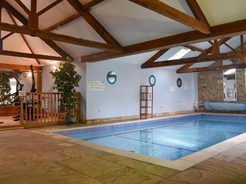 a large swimming pool in a house with wooden ceilings at Fox Cover Cottage in Great Edston