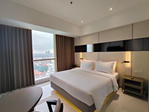 a bedroom with a white bed and a large window at Grand Whiz Hotel Praxis Surabaya in Surabaya