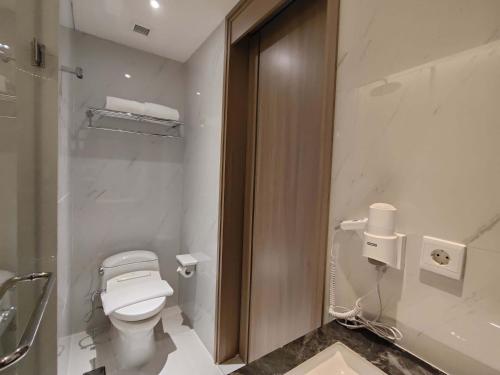 a white bathroom with a toilet and a shower at Grand Whiz Hotel Praxis Surabaya in Surabaya