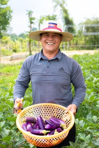 a man wearing a hat holding a basket of vegetables at Beng Mealea Lodge in Phumĭ Trach Pôk (2)
