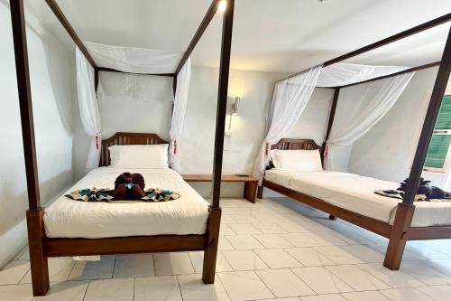 a bedroom with two beds with a teddy bear laying on a blanket at Sabaidee Chiangmai Hotel in Chiang Mai