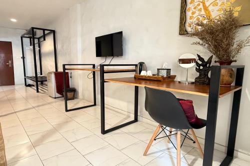 a room with a table and a chair and a television at Sabaidee Chiangmai Hotel in Chiang Mai