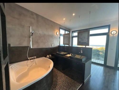 une grande salle de bain avec une baignoire et une grande fenêtre dans l'établissement Superbe Villa sur le mont Saint Clair à Sete, à Sète