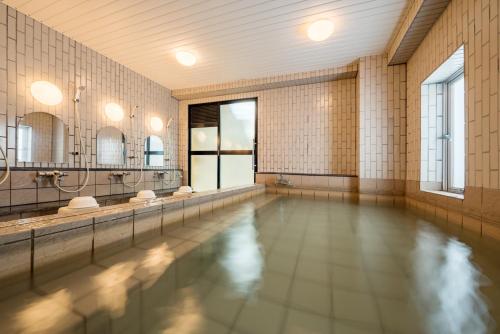 een zwembad in een badkamer met spiegels bij Green Hotel Kitakami in Kitakami