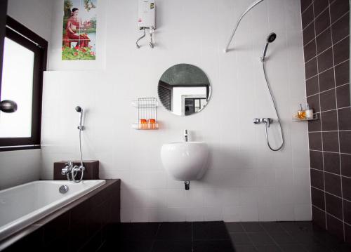 een badkamer met een bad, een wastafel en een spiegel bij Alphabeto Resort in Nai Harn Beach