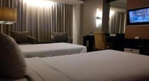 a hotel room with two beds and a flat screen tv at Grage Hotel Cirebon in Cirebon