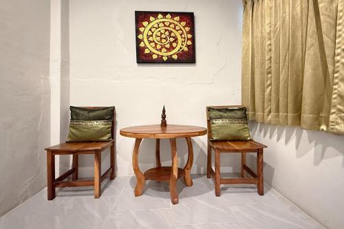 two chairs and a wooden table and a table and chairs at Sabaidee Chiangmai Hotel in Chiang Mai