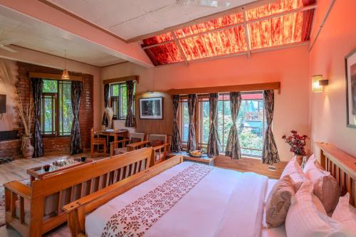 a large bedroom with a large bed and windows at SaffronStays The Divine Hima in Dharamshala