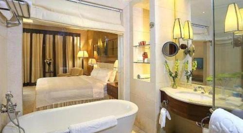 a bathroom with a tub and a bedroom with a bed at Regency Hotel in Shantou