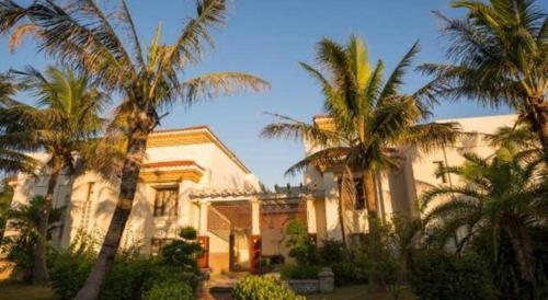 a building with palm trees in front of it at Ocean Spring Metropark Hotel Zhuhai in Zhuhai