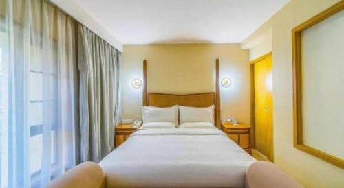 a large bed in a hotel room with a window at Ocean Spring Metropark Hotel Zhuhai in Zhuhai