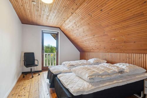a bedroom with three beds and a chair and a window at Modern Holiday Home With Sea View In Tejn in Sandkås
