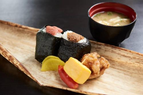 Un plato de madera con sushi y una taza de sopa. en Heiwadai Hotel Tenjin, en Fukuoka