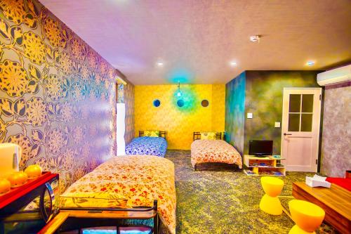 a bedroom with two beds and a colorful wall at ヴィラ犬山 in Inuyama
