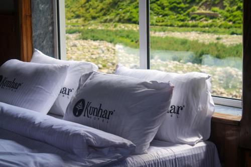 a pile of pillows sitting on a bed in front of a window at Kunhar Hotel RiverSide Block in Nārān