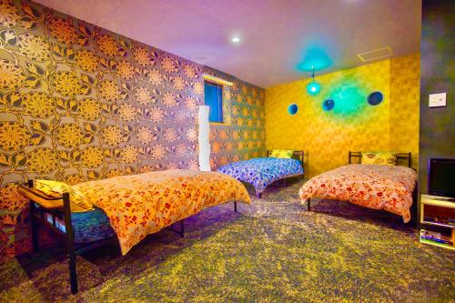 a bedroom with two beds and a wall with flowers at ヴィラ犬山 in Inuyama