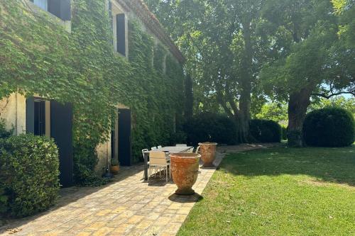 une terrasse avec une table et des chaises à côté d'une maison dans l'établissement GROOMI The Grand Mas Domaine du Moulin de Perdrix, à Mudaison