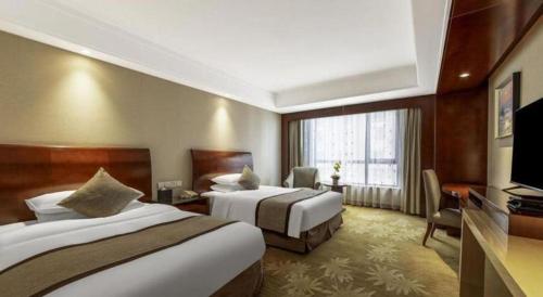 a hotel room with two beds and a television at Hohhot Hai Liang Plaza Hotel in Hohhot