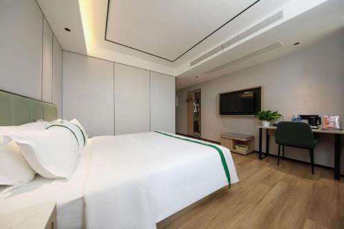 a bedroom with a large white bed and a desk at GreenTree Inn Anhui Xuancheng Ningguo NinGYAng East Road Darunfa Branch in Xuanzhou