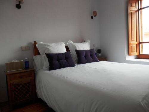 a bedroom with a large white bed with purple pillows at La Casona de Castilnovo - Gay Men Only in Valdesaz