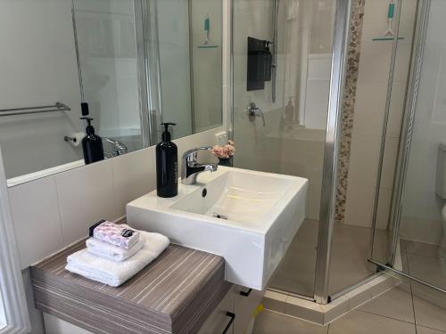 a white bathroom with a sink and a shower at Tranquil Getaways On Obi Maleny in Maleny