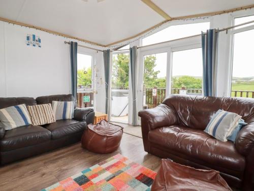 a living room with leather furniture and large windows at Orchard View in Tintagel