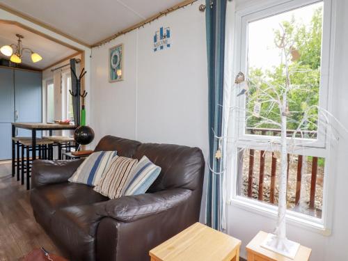 a living room with a leather couch and a window at Orchard View in Tintagel