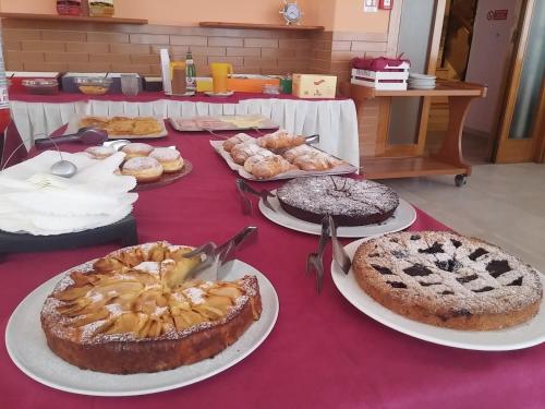 a table topped with cakes and other desserts on plates at Hotel Milena in Rimini