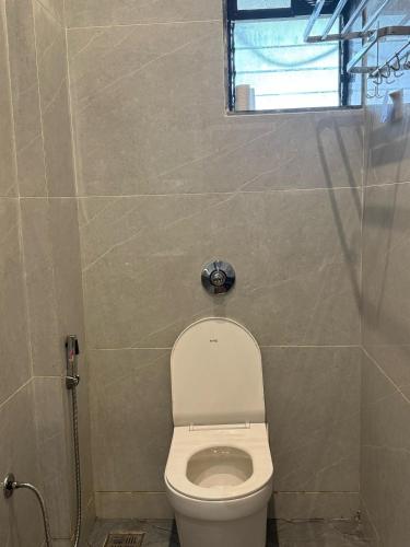 a small bathroom with a toilet and a window at Hotel The Ceremony in Kalyan