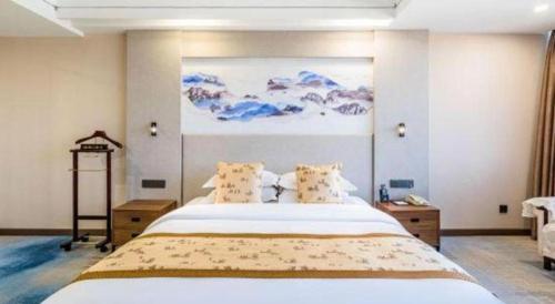 a bedroom with a large bed with a painting on the wall at Junyu Grand Hotel Qinhuangdao in Qinhuangdao