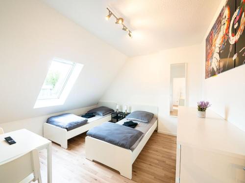 two beds in a white room with a table at Work & Enjoy Apartments in Ahrensburg in Ahrensburg