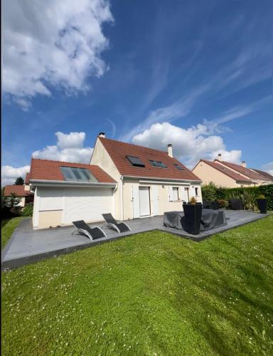 une maison avec deux chaises longues dans une cour dans l'établissement Villa Proche paris, à Servon