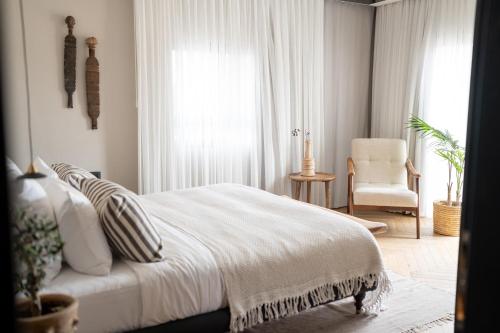a white bedroom with a bed and a chair at Doria Luxury Boutique Hotel in Dishon