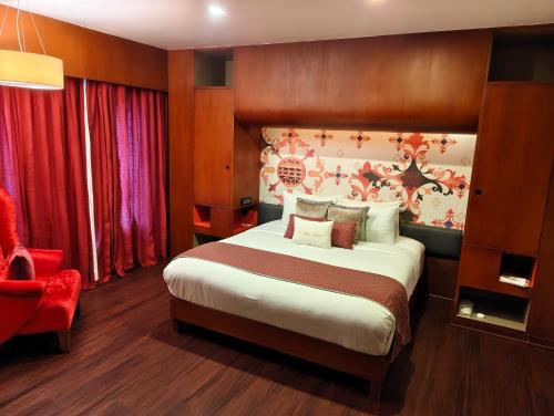 a bedroom with a large bed and a red chair at Zone By The Park, ORR, Chennai in Chennai