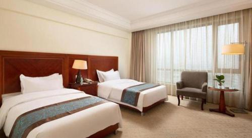 a hotel room with two beds and a chair at Changshu Jinling Tianming Grand Hotel in Suzhou