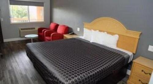 a hotel room with a bed and red chairs at Grand Park Inn in Baldwin Park