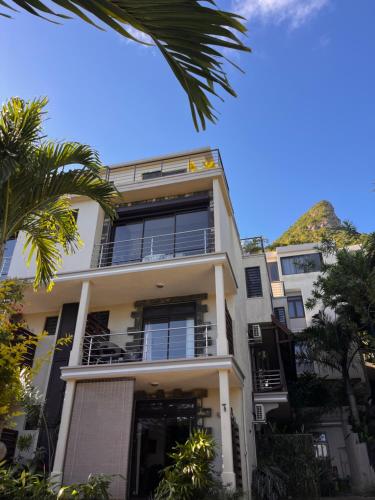 a tall white building with a mountain in the background at Joubarbe Residence in Moka
